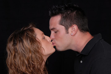 close up of young woman and man caught kissing .