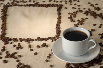 white cup of coffee and frame from coffee-beans