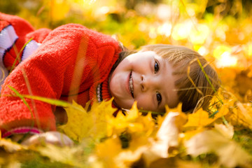 Happy girl lying on autumnal ground