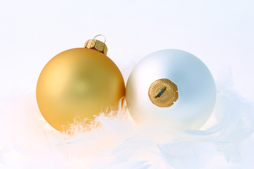 Golden and white christmas balls on white feathers