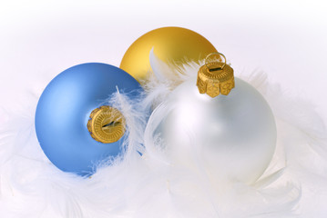 Golden, blue and white christmas balls on white feathers