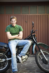Obraz na płótnie Canvas Portrait of young man sitting on motorbike