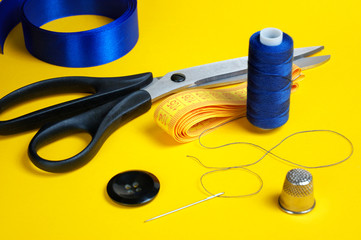 thread coils, measuring tape, thimble, scissors and a needle