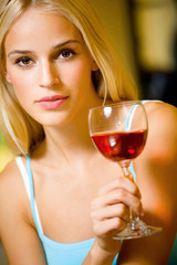 Portrait of young beautiful blond woman with redwine glass