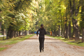 Zoom-in image of a woman running in an autumn park.