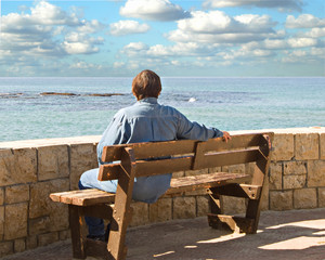 Woman sitting on a bench and looking to sea