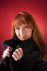 Romantic girl in fur coat over red background