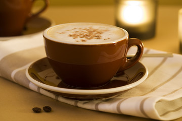 cup of flat white coffee on towel, candle in background