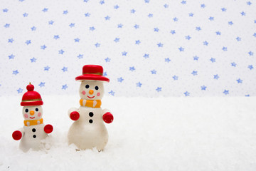 Snowman ornaments sitting on snow with a star background