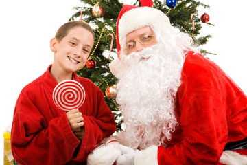 Fototapeta na wymiar Little boy holding a lollipop, together with Santa Claus.
