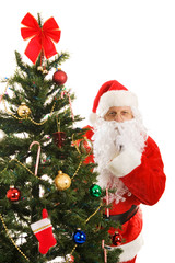 Santa Claus peeking around the Christmas tree