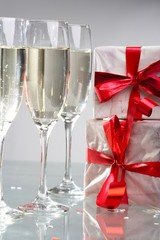 Glasses of champagne, gifts with red tapes and bows