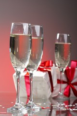 Glasses of champagne, gifts with red tapes and bows