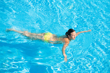 Young beautiful caucasian woman in bikini swimming in pool