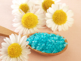 Fototapeta na wymiar bath salt in a spoon and flowers of daisy