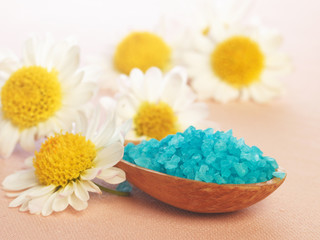 bath salt in a spoon and flowers of daisy