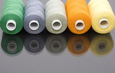 Five coloured thread, unlit background.