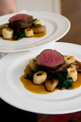 Gourmet beef medalions and vegetables with sauce on a white dish