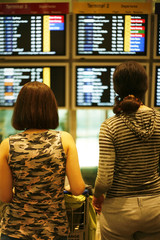 Two girls look a board at the airport