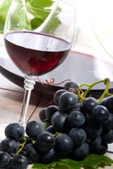 Glass of red wine, decanter and fresh cut black wine grape