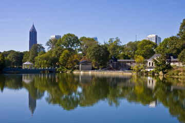A city skyline reflected in a calm blue park lake