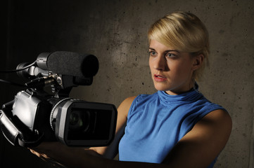 junge blonde Frau mit einer Videokamera