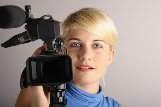 junge blonde Frau mit einer Videokamera