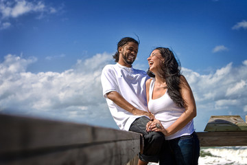 Couple laughing at the beach, blue sky in the back