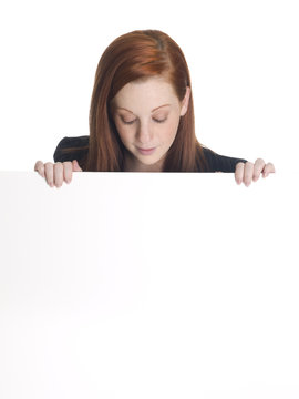 businesswoman looking over the edge of a blank white sign.