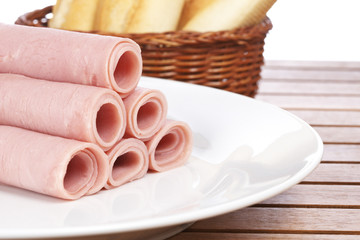 Rolled tasty ham on white dish and bread. Shallow DOF