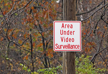 Video surveillance warning sign in a wooded area