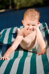Two years old baby boy enjoys sunshine in deckchair.