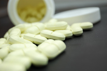 heap of pills and container on black (shallow DOF)