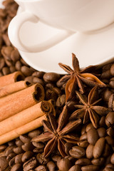 cup of coffee with whole beans, cinnamon and anise