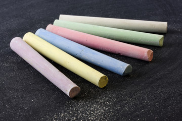 6 pieces of chalk in different color on blackboard