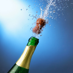 Bottle of champagne with splashes over blue background