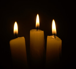 three candles over black background