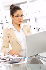 Business woman working in office, looking at camera and smiling