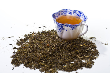 Cup of tea and loose tea leaves on white