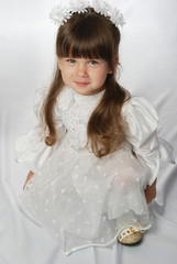 The girl in a white dress on white satin