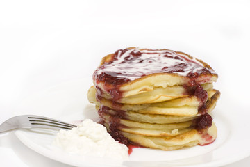 Pile of pancakes with cream and raspberry jam