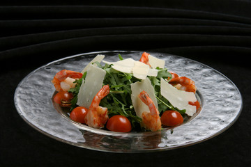 Salad from rukkola with shrimps, tomatoes.