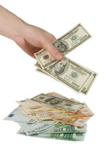 Hand putting dollar bills on a pile of one-hundred euro bills