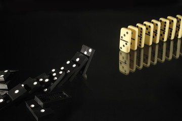 Black and white dominoes on dark glassy background