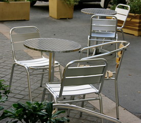Terrasse de caf&eacute; avec tables et chaises en m&eacute;tal.