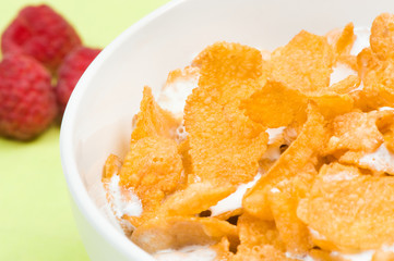 bowl of corn flakes with raspberry on background
