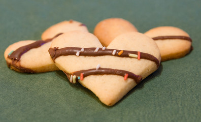 Three heartshaped cookies on green background
