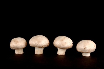 Four fresh cuted champignons isolated on black background.
