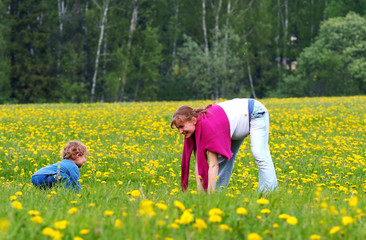 young pregnant woman and her son in field of dandelion