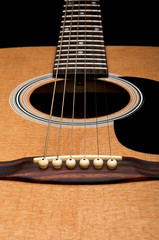 Obraz premium Close-up of acoustic guitar, focus on the bridge, on black backg
